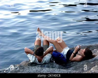 Couple de détente sur les rochers côtiers, Riomaggiore, Cinque Terre, Italie Banque D'Images