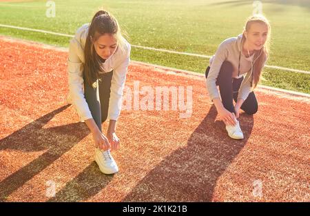 Deux filles en vêtements de sport posant au stade.Portrait de deux amies sportives au stade.Sport et vie saine. Banque D'Images