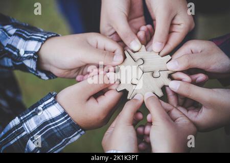 Les mains de diverses personnes assemblant le puzzle, l'équipe des jeunes ensemble des pièces à la recherche de la bonne correspondance, aider à soutenir le travail d'équipe pour trouver le commun ainsi Banque D'Images