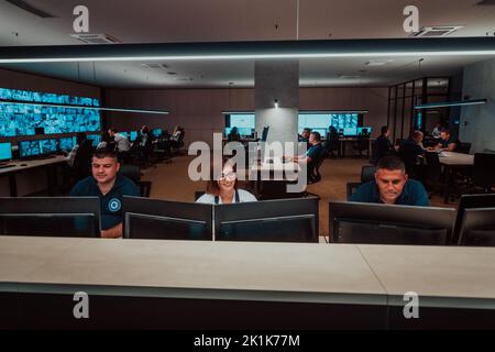 Groupe d'opérateurs de centre de données de sécurité travaillant dans une salle de surveillance CCTV regardant sur plusieurs moniteurs officiers surveillant plusieurs écrans Banque D'Images