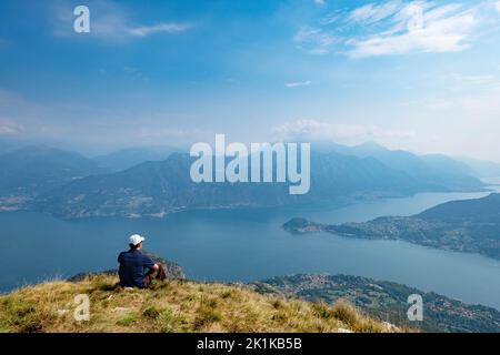 Homme assis sur Monte Crocione regardant le lac de Côme, Lugano Prealps, Lombardie, Italie Banque D'Images