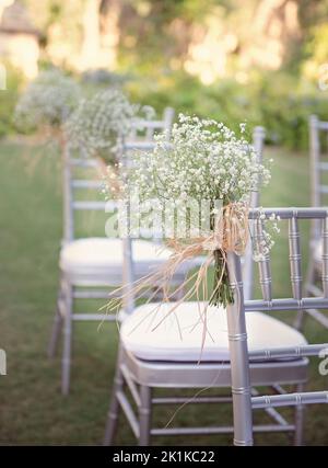 Gros plan de fleurs de Gypsophila liées à des chaises pour un mariage en plein air dans un jardin Banque D'Images