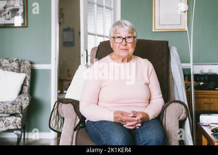 Portrait d'une grand-mère âgée, mûre et souriante, à la retraite, à lunettes, femme âgée souriant, assise sur le fauteuil à la maison, profitant de la retraite. Séle Banque D'Images