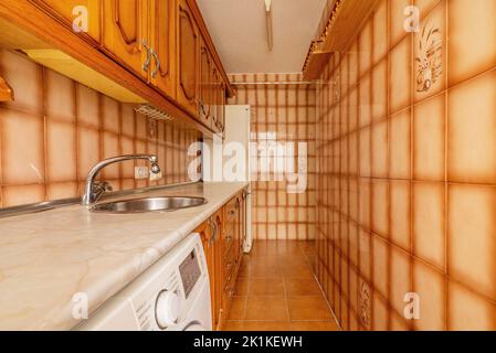 Cuisine avec comptoir en imitation de marbre de couleur crème, carrelage orange-brun et mobilier rustique en bois Banque D'Images