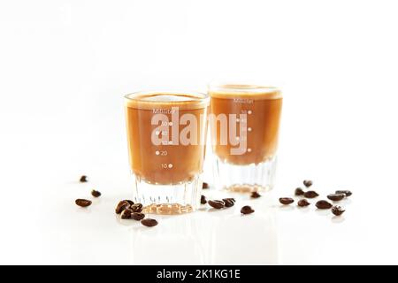 Deux doses de café avec du lait et des grains de café rôtis sur une table Banque D'Images