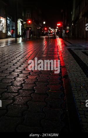 Un trottoir humide la nuit dans les lumières dans le centre de la vieille ville de Porto, Portugal. Banque D'Images