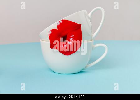 Deux tasses en céramique blanche décorées de lèvres rouges. Concept de la fête des mères heureuse. Espace pour le texte. Banque D'Images