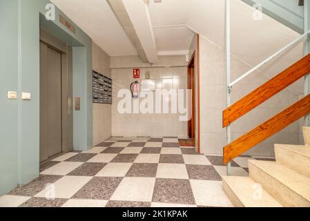 Palier entre les étages d'un bâtiment avec des escaliers en terrazzo et ascenseur avec des portes en acier inoxydable Banque D'Images