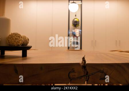 Vue à angle bas d'une longue table en bois naturel avec vitrine et placard blanc en arrière-plan Banque D'Images