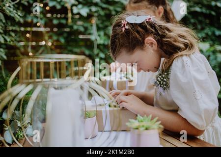 Petites filles préparant le cadeau pour la mariée à la fête de jardin de mariage. Banque D'Images