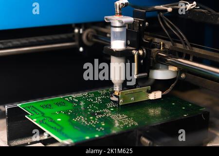 Manipulateur automatique avec aiguille distribuant la pâte à souder sur la carte de circuit imprimé de l'ordinateur CMS. Photo de haute qualité Banque D'Images