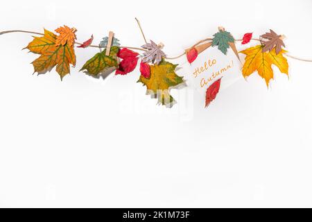 Composition créative de bordure de cadre d'automne avec feuilles d'automne. Les feuilles d'automne rouges et jaunes pendent sur corde à linge, sur fond blanc espace de copie pour t Banque D'Images