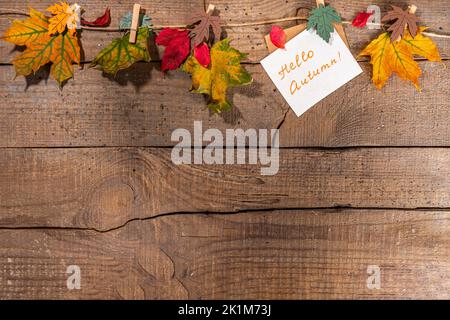 Composition créative de bordure de cadre d'automne avec feuilles d'automne. Les feuilles d'automne rouges et jaunes pendent sur corde à linge, sur fond de bois pour copier l'espace Banque D'Images