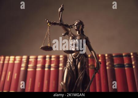 photo de la statue de droit de bronze tenant l'équilibre entre le bien et le mal devant la rangée de livres dans une université Banque D'Images