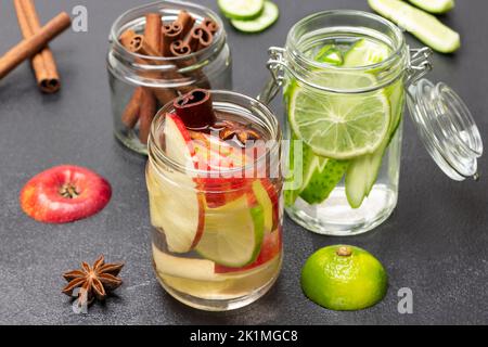Eau infusée à la cannelle, à la pomme et au concombre dans un pot en verre. Bâtonnets de cannelle dans un pot en verre. Arrière-plan noir. Vue de dessus Banque D'Images
