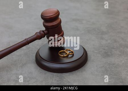 Thème droit. Jugez les anneaux de mariage de gavel sur fond gris en pierre de béton. Procédure de divorce. Maillet de juge qui décide du divorce de mariage, de l'accord matrimonial, des légalités du divorce Banque D'Images