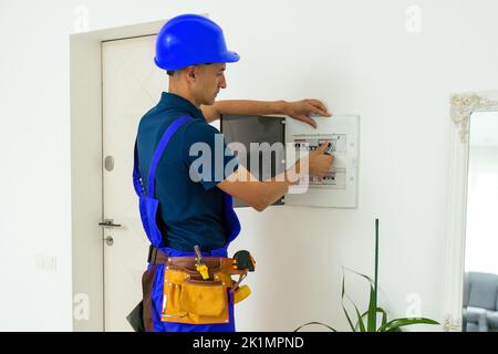 Électricien au travail, examine la connexion de câble dans la ligne électrique dans le fuselage d'un tableau de commutation industriel. Professionnel Banque D'Images