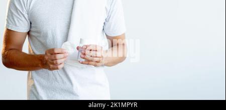 Soins de la peau pour hommes. Nettoyage du visage. Produit cosmétique. Homme de sport méconnaissable en t-shirt blanc serviette tenant tonique dans un petit tampon en coton clair de bouteille dans Banque D'Images