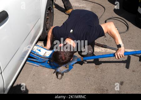 Jeune homme travailleur changeant un pneu sur la roue d'une voiture à Llandovery pays de Galles Carmarthenshire Royaume-Uni KATHY DEWITT Banque D'Images