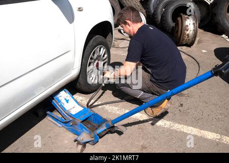 Jeune homme travailleur changeant pompe un pneu sur la roue d'une voiture à Llandovery pays de Galles Carmarthenshire Royaume-Uni KATHY DEWITT Banque D'Images