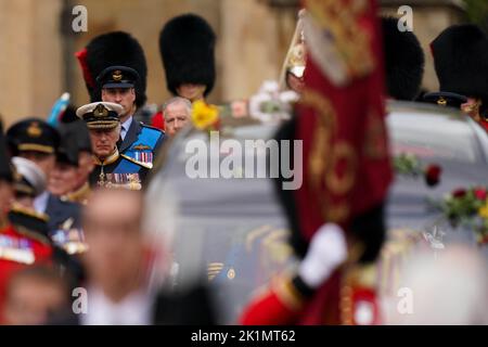 Le roi Charles III et le prince de Galles suivent l'audience d'État porte le cercueil de la reine Elizabeth II, drapé dans la norme royale avec la Couronne d'État impériale et l'orbe et le séctrice du souverain, pendant la procession cérémoniale à travers le château de Windsor, à un service de committal à la chapelle Saint-Georges. Date de la photo: Lundi 19 septembre 2022. Banque D'Images