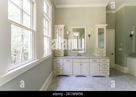 Salle de bains vert sauge avec bordure blanche de douvres, baignoire autonome, douche fermée avec verre en briques à chevrons peintes en blanc, comptoir en granit Banque D'Images