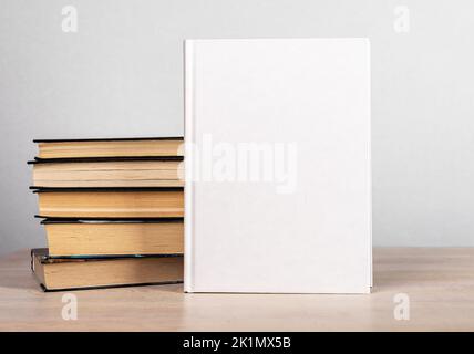 La maquette et les romans s'empilent sur une table en bois. Modèle avec couverture blanche. Littérature, éducation, concept de lecture. Publicité du nouveau volume. Bonjour Banque D'Images