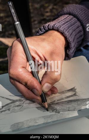 La main de l'artiste esquissant un dessin au crayon. Gros plan.textures de peau. Banque D'Images