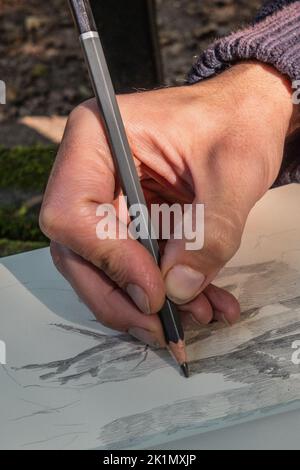 La main de l'artiste esquissant un dessin au crayon. Gros plan.textures de peau. Banque D'Images