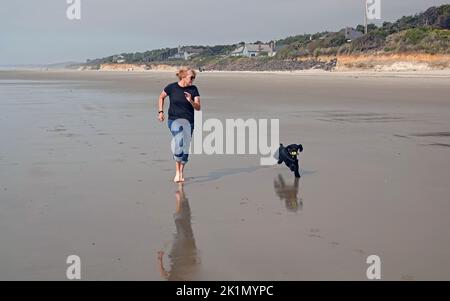 Une femme âgée court le long d'une plage près de Yachats, en Oregon, avec son chiot d'épagneul cocker. Banque D'Images