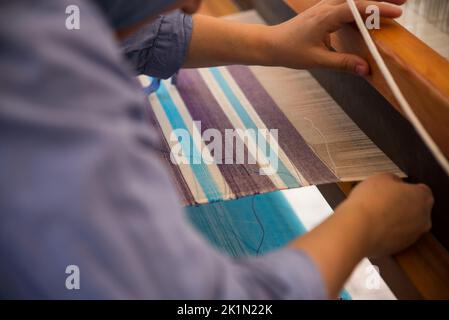 Tissage de tapis en utilisant des techniques traditionnelles sur un métier à tisser. , gros plan du tissage et de la production de tapis à la main. Banque D'Images