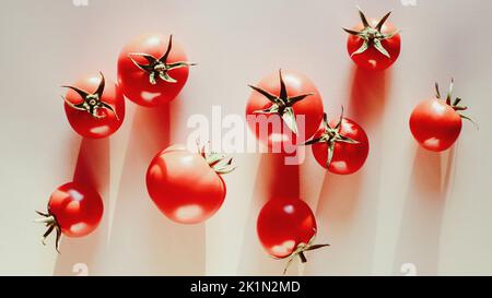 Tomates dispersées sur une table de cuisine beige, lumière et ombres, nourriture fond plat Banque D'Images