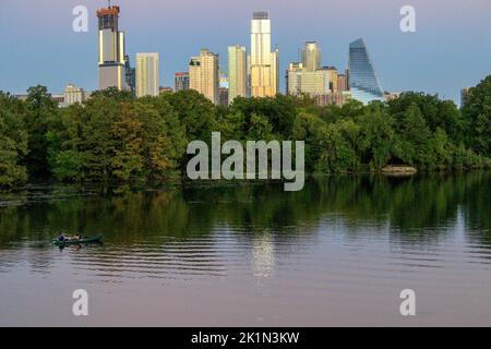 Kayak sur le fleuve Colorado dans le centre-ville d'Austin, Texas, tandis que les couchers de soleil reflètent la lumière et les ombres le long de la rivière. Banque D'Images