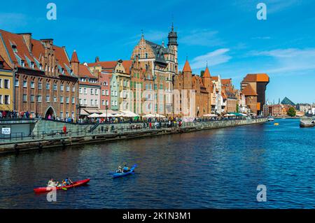 Remblai de la rivière Motlawa à Gdansk. Vieilles maisons en briques et grue. Les touristes sur des kayaks flottent le long de la rivière Motlawa Banque D'Images