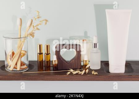 Produits d'hygiène bucco-dentaire biologiques. Composition écologique avec dentifrice bio, brosses à dents en bois dans un pot en verre sur une étagère en bois dans une salle de bains. Naturel Banque D'Images