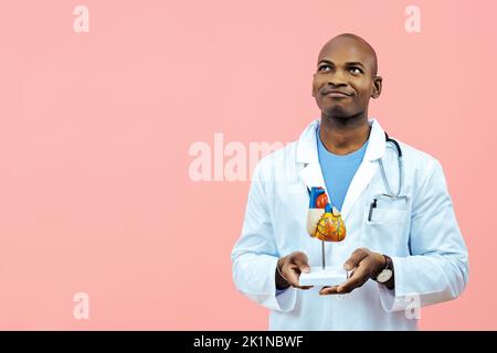 Médecin portant une blouse de laboratoire tenant un modèle de coeur regardant l'espace de copie à l'intérieur du studio Banque D'Images