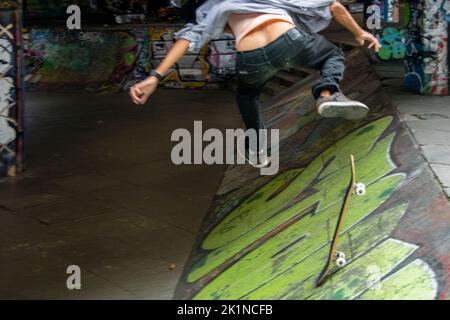 Skateboarder essayant de flip-trick dans un haut spee dans un skatepark dans la ville Banque D'Images