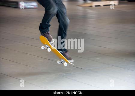 Skateboarder essayant de flip-trick dans un haut spee dans un skatepark dans la ville Banque D'Images