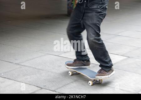 Skateboarder essayant de flip-trick dans un haut spee dans un skatepark dans la ville Banque D'Images