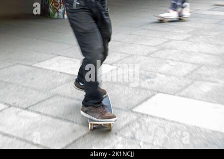 Skateboarder essayant de flip-trick dans un haut spee dans un skatepark dans la ville Banque D'Images