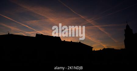 View of an evening orange sky with contrails Stock Photo