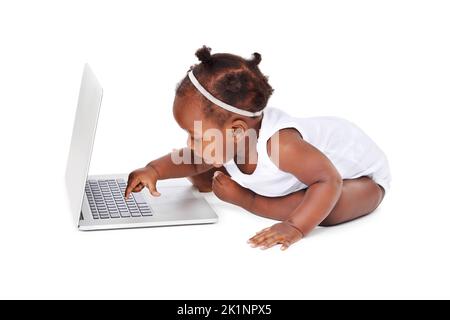 Je laisse télécharger ma vidéo. Studio photo d'une adorable petite fille à l'aide d'un ordinateur portable isolé sur blanc Banque D'Images