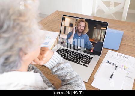 Femme de race blanche discutant sur un webinaire avec un collègue de travail sur ordinateur portable Banque D'Images