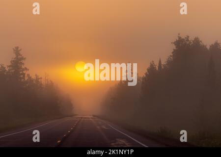 Lever du soleil sur une matinée d'automne brumeuse sur l'autoroute 77 à Clam Lake, Wisconsin. Banque D'Images