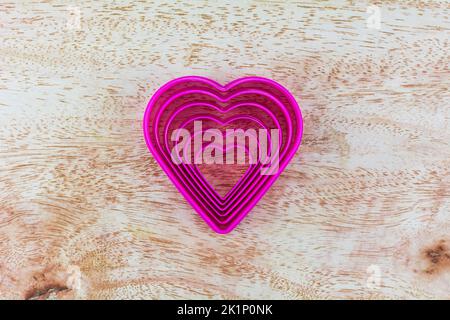 Heart shaped fried egg blocks on wooden background. Stock Photo