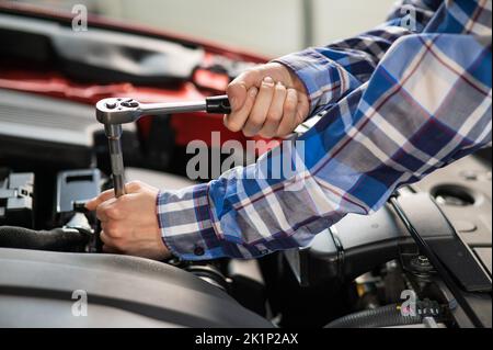 Mécanique automobile femelle en dévissant un écrou pour remplacer une bougie d'allumage de voiture. Banque D'Images