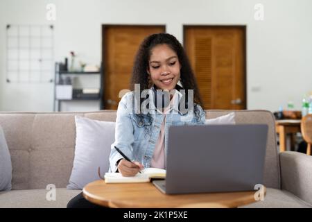 Portrait femme portant des écouteurs regarder le webinaire écrire des notes étudier en ligne avec un professeur en ligne, une étudiante africaine apprenant la langue ordinateur Banque D'Images