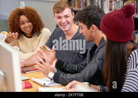 Le groupe de bibliothèques. Groupe d'étudiants travaillant ensemble à un ordinateur dans une bibliothèque universitaire Banque D'Images