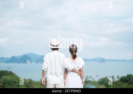 Joyeux couple voyageur en chemise blanche et robe profiter de la belle vue, les touristes avec debout et se détendre sur l'océan. Voyage, ensemble, amour, été an Banque D'Images