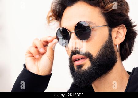 jeune homme avec la barbe en train de mettre des lunettes de soleil Banque D'Images